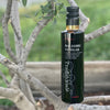 Stylishly printed bottle of Traditional Balsamic Vinegar nestled in the branches of a young olive tree.