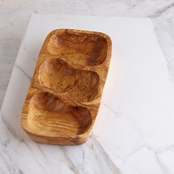 Olive Wood Three Section Tray is shown on a marble board. The openings are irregular in shape, but for this particular sample, they are of similar size.